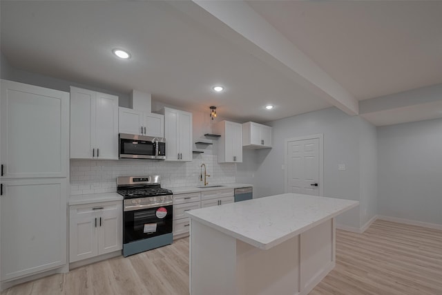 kitchen with stainless steel appliances, a sink, light wood finished floors, backsplash, and white cabinetry