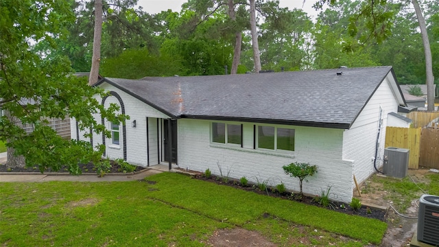 ranch-style home with a shingled roof, cooling unit, and brick siding