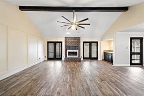 15418 Windy Cove Dr, Houston, TX 77095 - unfurnished living room featuring beamed ceiling, a brick fireplace, french doors, high vaulted ceiling, and wood finished floors