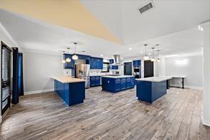 15418 Windy Cove Dr, Houston, TX 77095 - kitchen featuring blue cabinets, a kitchen island, a peninsula, baseboards, and wood finished floors