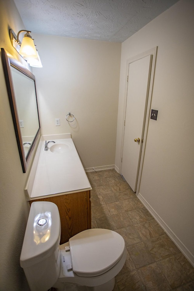 21926 Crestworth Ln, Katy, TX 77449 - half bathroom with vanity, toilet, stone finish floors, baseboards, and a textured ceiling