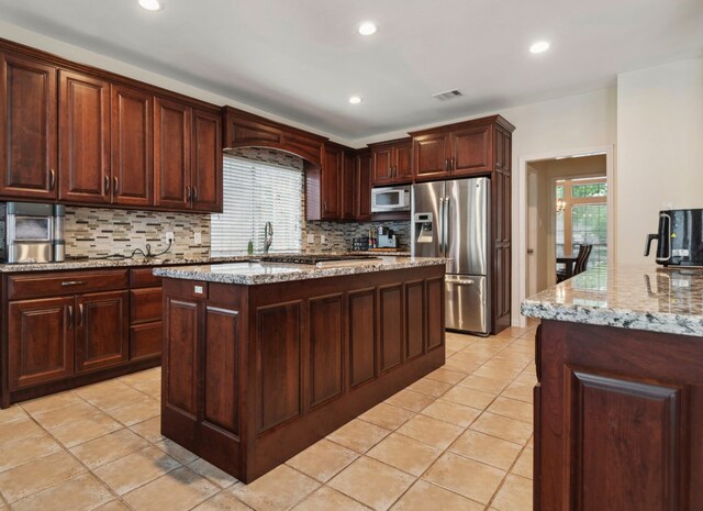 kitchen with stainless steel refrigerator with ice dispenser, white microwave, tasteful backsplash, a sink, and light tile patterned flooring