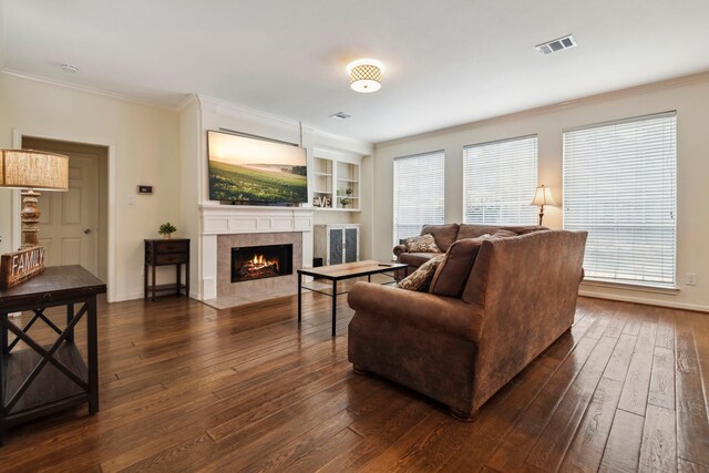 living area featuring dark wood finished floors, ornamental molding, a tile fireplace, and baseboards