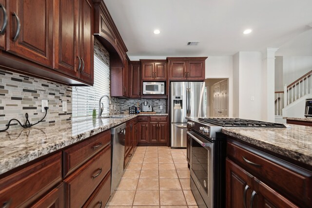 kitchen featuring stainless steel appliances, a sink, light stone counters, tasteful backsplash, and light tile patterned flooring