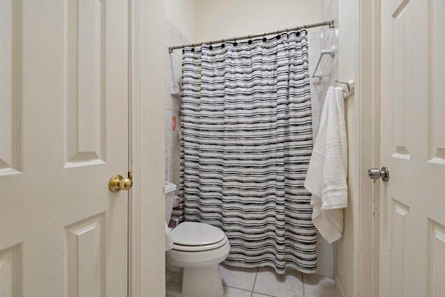 bathroom with tile patterned floors, toilet, and curtained shower