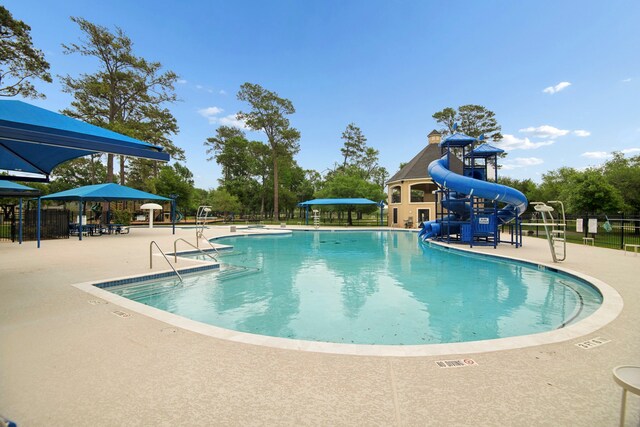 community pool with a water slide, a patio, and fence