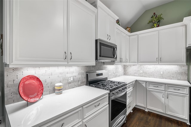 kitchen with stainless steel appliances, light countertops, vaulted ceiling, tasteful backsplash, and dark wood-style floors
