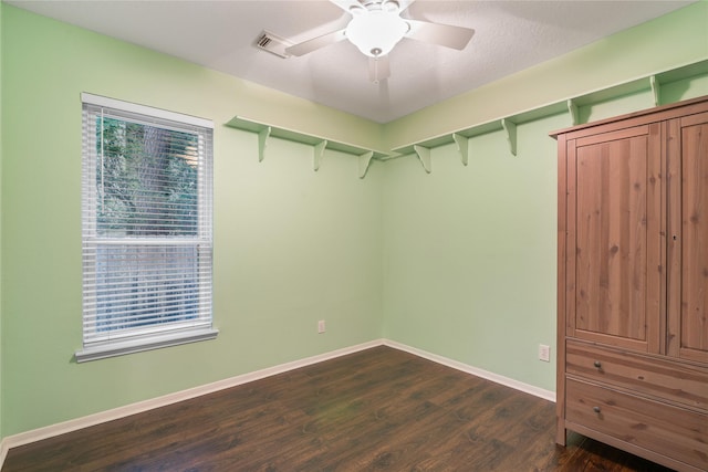 spacious closet with dark wood-style flooring and a ceiling fan