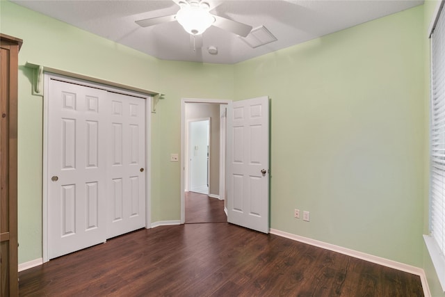 unfurnished bedroom with dark wood-type flooring, baseboards, a closet, and ceiling fan