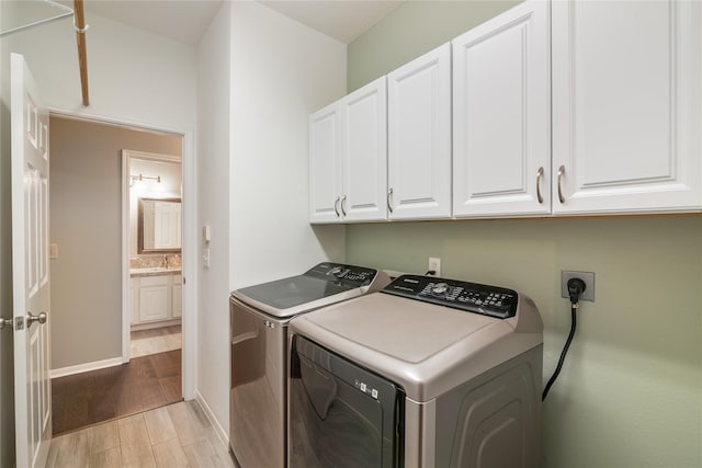 laundry room with cabinet space, washer and dryer, light wood-type flooring, and baseboards