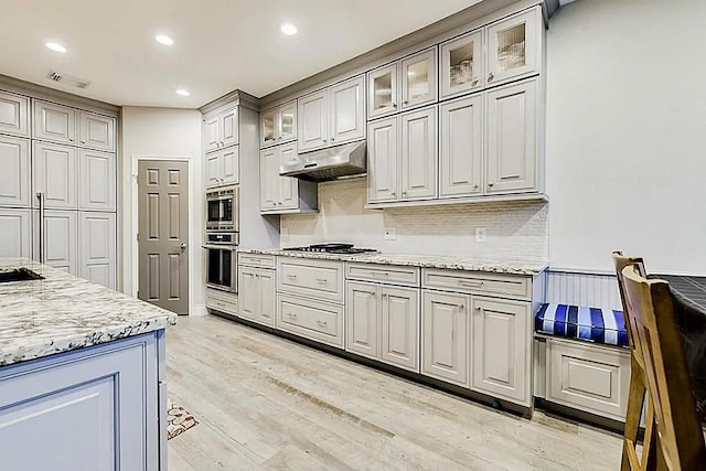 15538 Pine Valley Trl, Cypress, TX 77433 - kitchen with under cabinet range hood, stainless steel appliances, recessed lighting, light wood-style flooring, and decorative backsplash