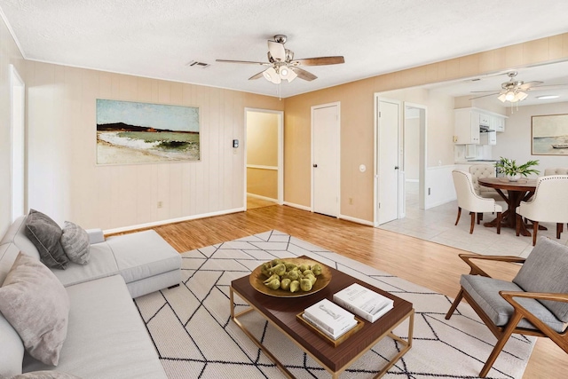 11802 Hamblin Rd, Cypress, TX 77429 - living area with a ceiling fan, light wood finished floors, baseboards, and a textured ceiling