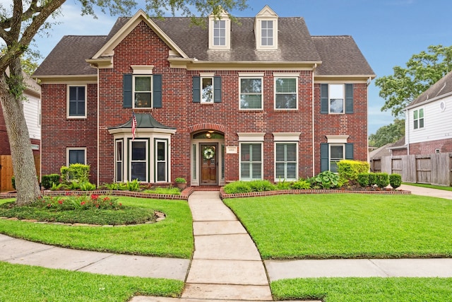 colonial inspired home featuring brick siding and roof with shingles