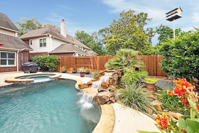 view of swimming pool featuring a fenced backyard, a pool with connected hot tub, and area for grilling