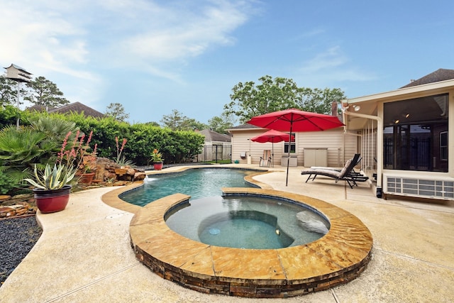 view of pool featuring a patio area, fence, and a pool with connected hot tub