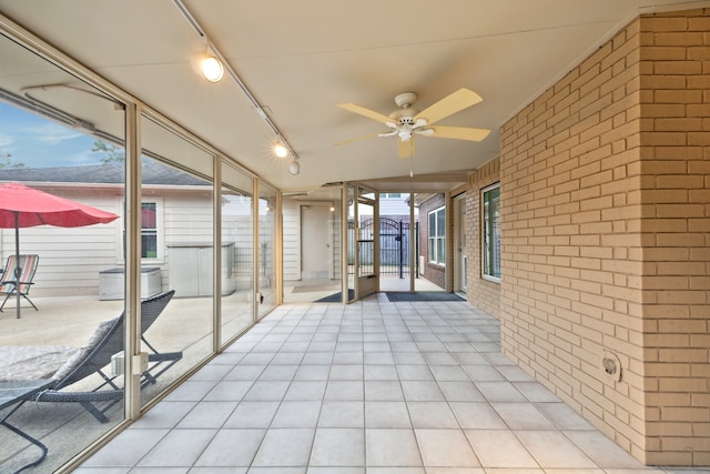unfurnished sunroom with a ceiling fan and rail lighting