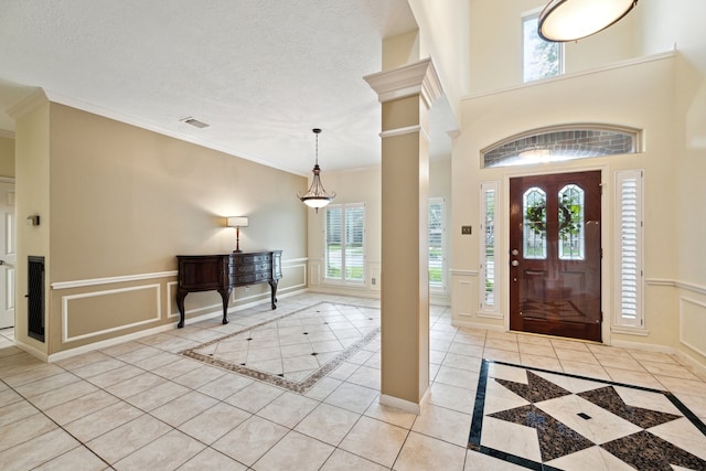 entryway featuring inlaid floor details, plenty of natural light, ornamental molding, a decorative wall, and light tile patterned flooring