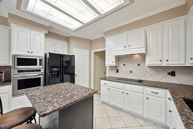 kitchen with black appliances, white cabinets, decorative backsplash, dark stone counters, and ornamental molding