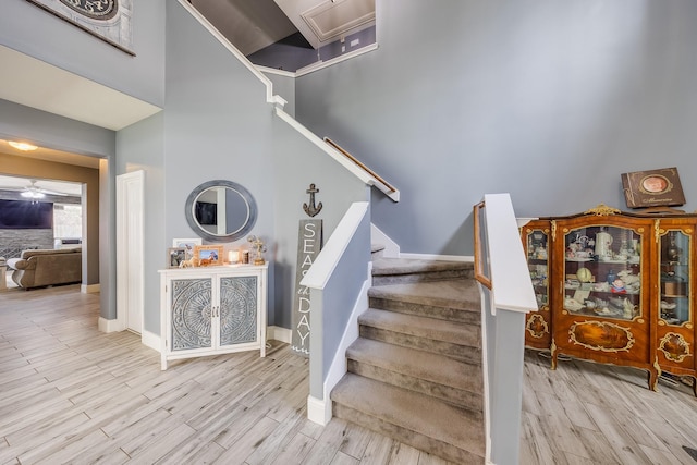 17611 Wind Mist Ln, Cypress, TX 77433 - stairway featuring wood finished floors, baseboards, and a towering ceiling