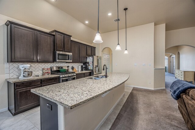 214 San Bernard Dr, Baytown, TX 77523 - kitchen with appliances with stainless steel finishes, a sink, arched walkways, dark brown cabinetry, and high vaulted ceiling