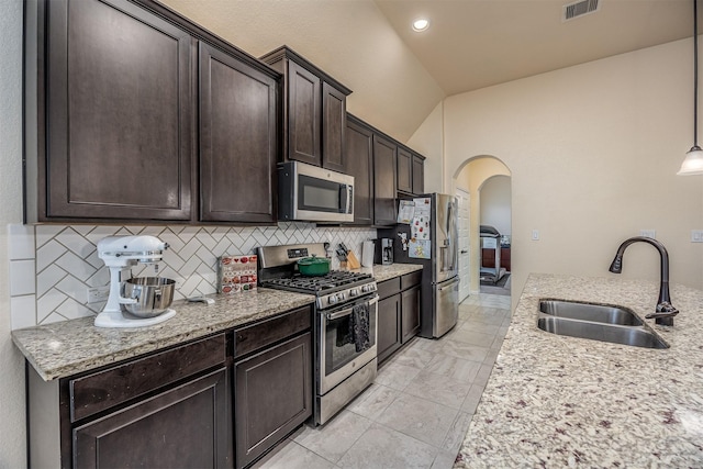 214 San Bernard Dr, Baytown, TX 77523 - kitchen with stainless steel appliances, a sink, arched walkways, dark brown cabinets, and decorative backsplash