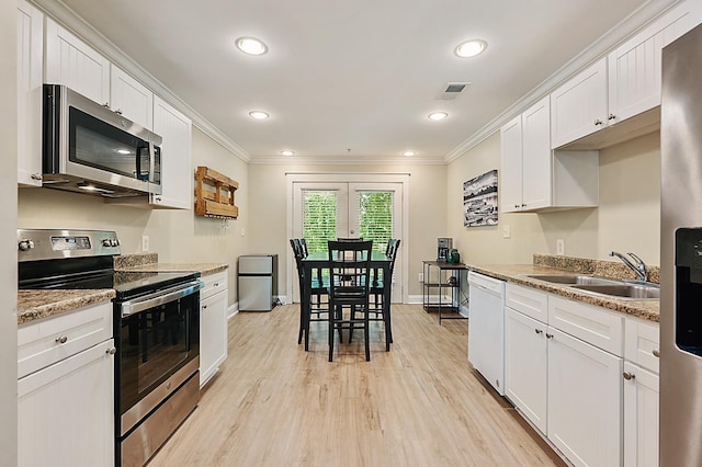 1725 Harvey Mitchell Pkwy S Unit 211, College Station, TX 77840 - kitchen featuring appliances with stainless steel finishes, crown molding, light wood-style flooring, a sink, and white cabinets
