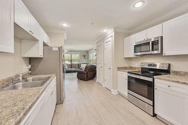 1725 Harvey Mitchell Pkwy S Unit 211, College Station, TX 77840 - kitchen with appliances with stainless steel finishes, a sink, ornamental molding, light wood-type flooring, and white cabinetry