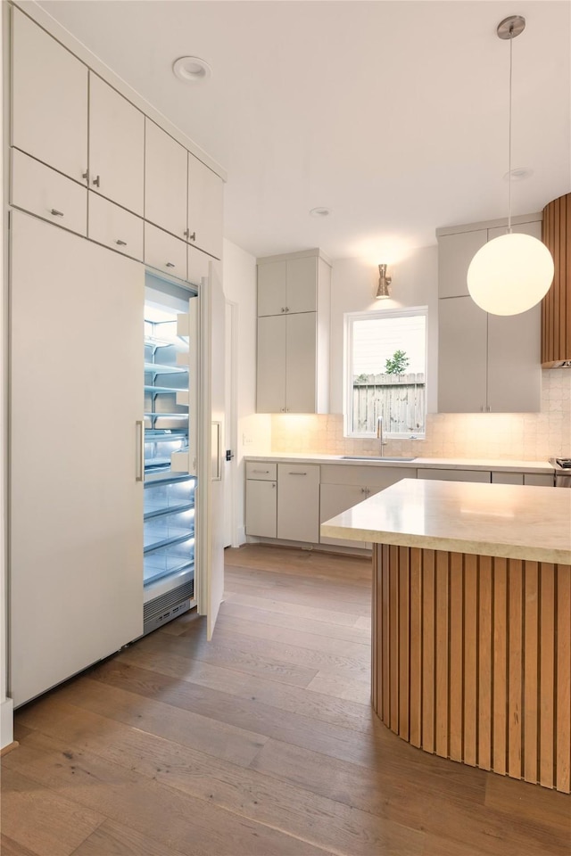 966 Lamonte Ln, Houston, TX 77018 - kitchen with light countertops, backsplash, light wood-type flooring, a sink, and hanging light fixtures
