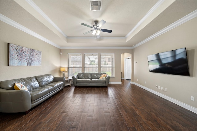 living room featuring a tray ceiling, ceiling fan, dark wood-style flooring, arched walkways, and crown molding
