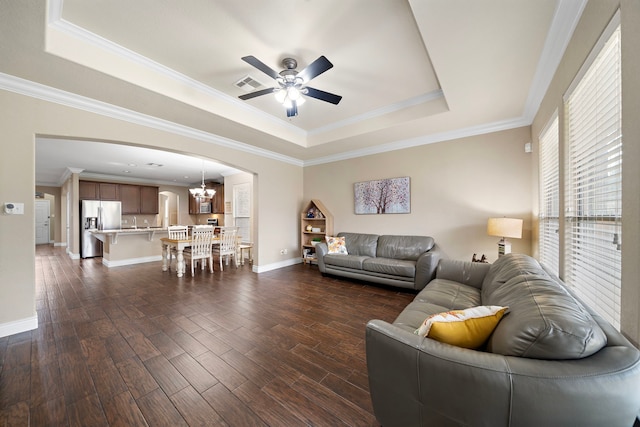 living room with a tray ceiling, arched walkways, ceiling fan, dark wood-style flooring, and ornamental molding