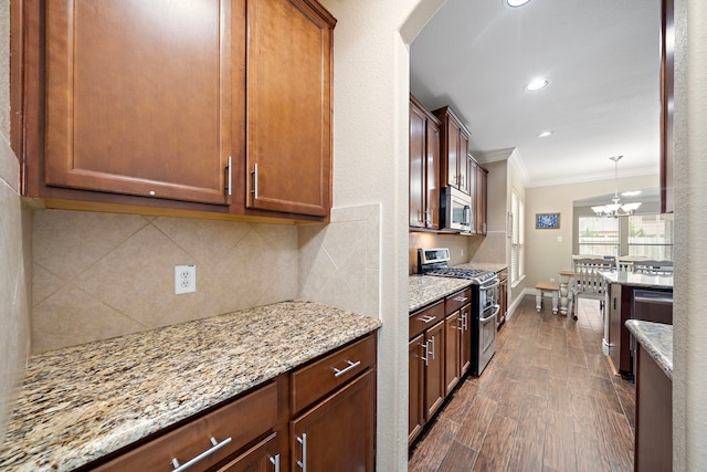 kitchen featuring appliances with stainless steel finishes, crown molding, light stone counters, backsplash, and dark wood-type flooring