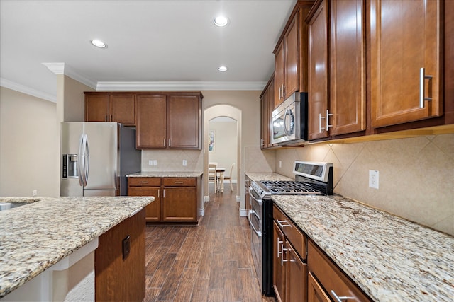 kitchen featuring stainless steel appliances, arched walkways, ornamental molding, light stone counters, and recessed lighting