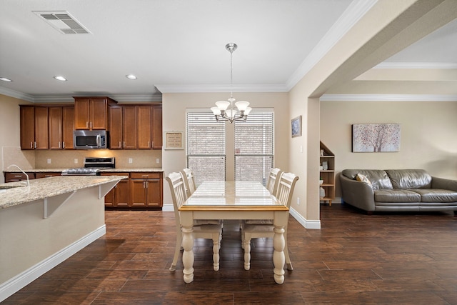 kitchen with appliances with stainless steel finishes, a chandelier, recessed lighting, light stone counters, and dark wood finished floors