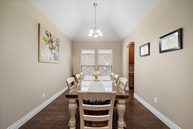 dining room featuring arched walkways, dark wood-style floors, a chandelier, vaulted ceiling, and baseboards