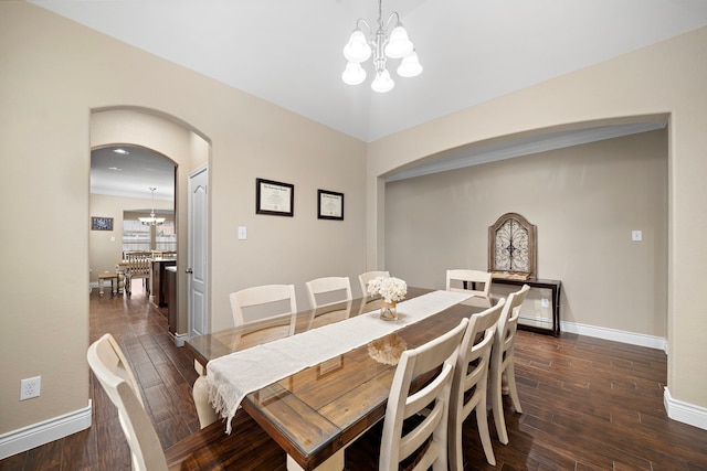 dining area featuring a chandelier, arched walkways, and baseboards