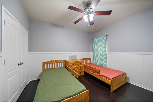 bedroom with hardwood / wood-style floors, a wainscoted wall, and a ceiling fan