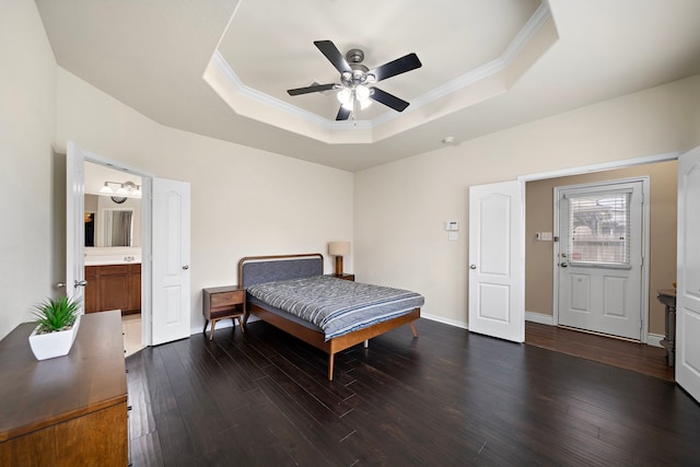 bedroom with a tray ceiling, wood finished floors, ornamental molding, connected bathroom, and a ceiling fan