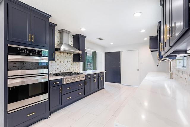 kitchen with appliances with stainless steel finishes, wall chimney range hood, decorative backsplash, plenty of natural light, and recessed lighting