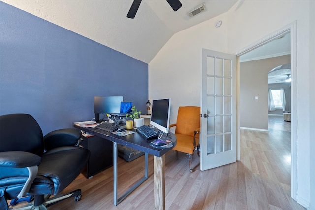 office featuring a ceiling fan, light wood-style flooring, lofted ceiling, and arched walkways