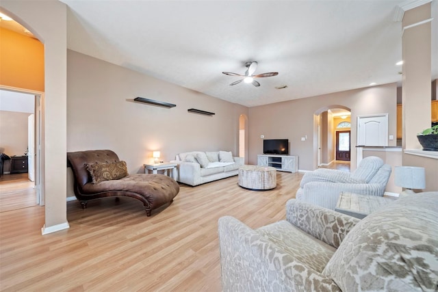 living area featuring arched walkways, ceiling fan, light wood-type flooring, baseboards, and recessed lighting