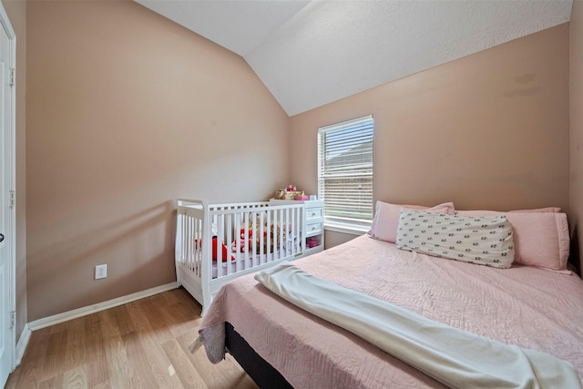 bedroom with lofted ceiling, wood finished floors, and baseboards