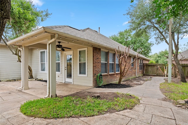 view of front of home featuring a ceiling fan, a patio area, fence, a shingled roof, and brick siding