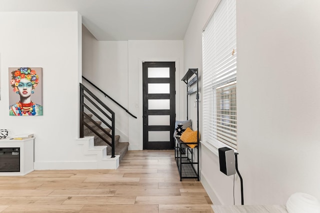 entryway featuring light wood-style floors, stairs, and baseboards