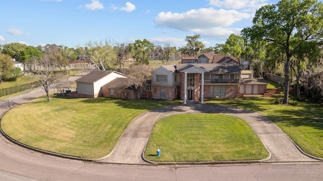 view of front of house featuring curved driveway, brick siding, and a front yard