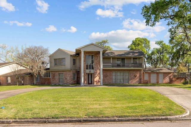 view of front of house with brick siding, a front lawn, and curved driveway