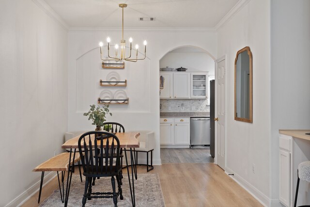 2838 Sunburst Ln, Montgomery, TX 77356 - dining area with a chandelier, crown molding, light wood-style floors, baseboards, and arched walkways