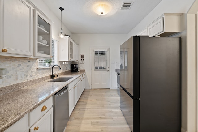 2838 Sunburst Ln, Montgomery, TX 77356 - kitchen with a sink, stainless steel appliances, light wood-type flooring, glass insert cabinets, and white cabinetry