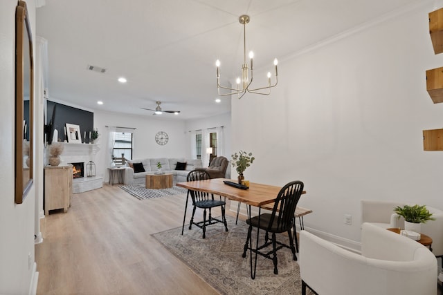 2838 Sunburst Ln, Montgomery, TX 77356 - dining space featuring light wood-type flooring, crown molding, recessed lighting, a lit fireplace, and ceiling fan