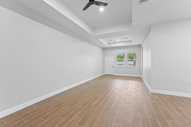 spare room with a raised ceiling, ceiling fan, baseboards, wood finished floors, and recessed lighting