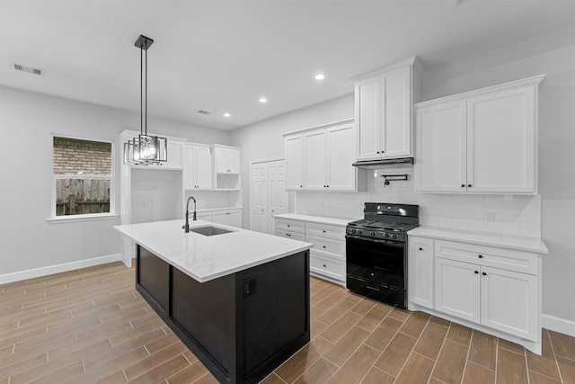 kitchen with black gas stove, a sink, baseboards, decorative backsplash, and recessed lighting